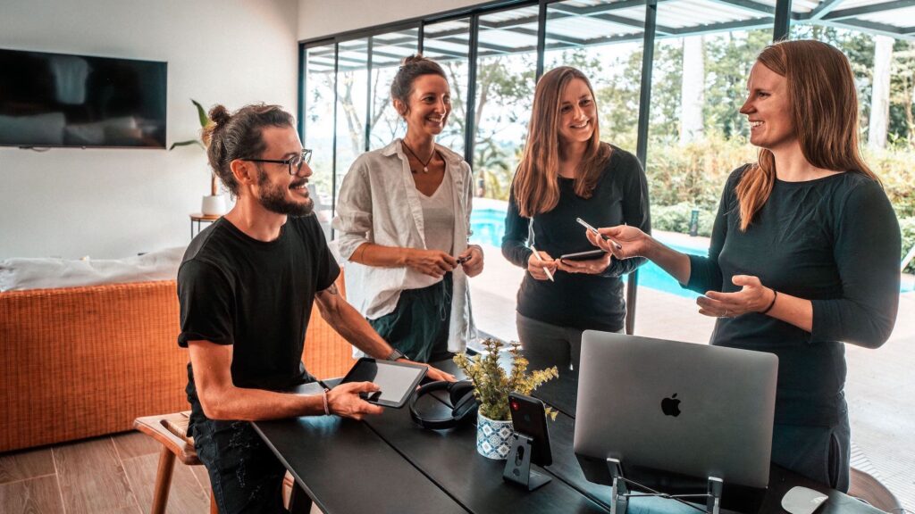 Das SMART SEO Team bestehend aus vier Personen steht an einem Tisch und Anna Hopfengärtner, Virtuelle Assistenz für SEO führt das Gespräch mit ihren Team Mitgliedern.